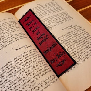 Könnte beinhalten: Ein rotes Lesezeichen mit schwarzem Text, der "Beware, for I am fearless, and therefore powerful" und "Frankenstein, Mary Shelley" lautet.