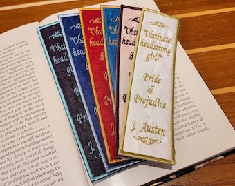 May include: A set of six colorful bookmarks with embroidered text. The bookmarks feature the titles of classic novels, including "Pride and Prejudice", "Obstinate Headstrong Girl", and "Sense and Sensibility".
