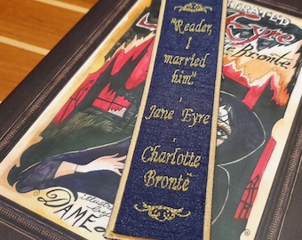 May include: A blue fabric bookmark with gold embroidery. The bookmark features a quote from Jane Eyre by Charlotte Bronte: "Reader, I married him."