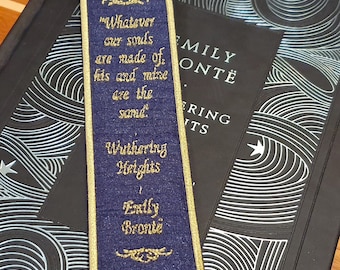 May include: A blue bookmark with gold embroidery featuring a quote from Emily Brontë's Wuthering Heights: "Whatever our souls are made of his and mine are the same."