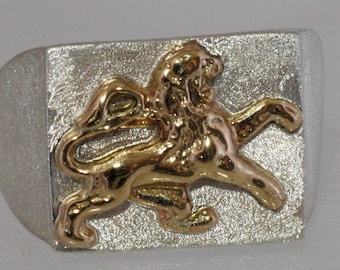 May include: A silver ring with a gold lion design. The lion is in a running pose with its mouth open.