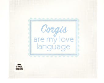 May include: White canvas with a light blue stitched design. The text "Corgis are my love language" is inside a light blue scalloped border. The Rowdy Designs logo is in the lower left corner.