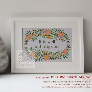 May include: A framed cross-stitch piece with the text "It is well with my soul" surrounded by a floral wreath. The frame is white, and the cross-stitch design features pink, yellow, and green colors. The dimensions are 7.4" x 5.4".