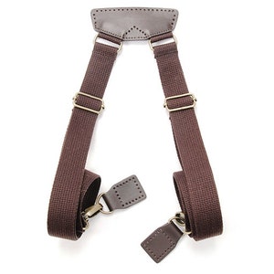 May include: Brown canvas shoulder straps with leather accents and brass hardware. The straps are designed to be used for a bag or other carrying device.