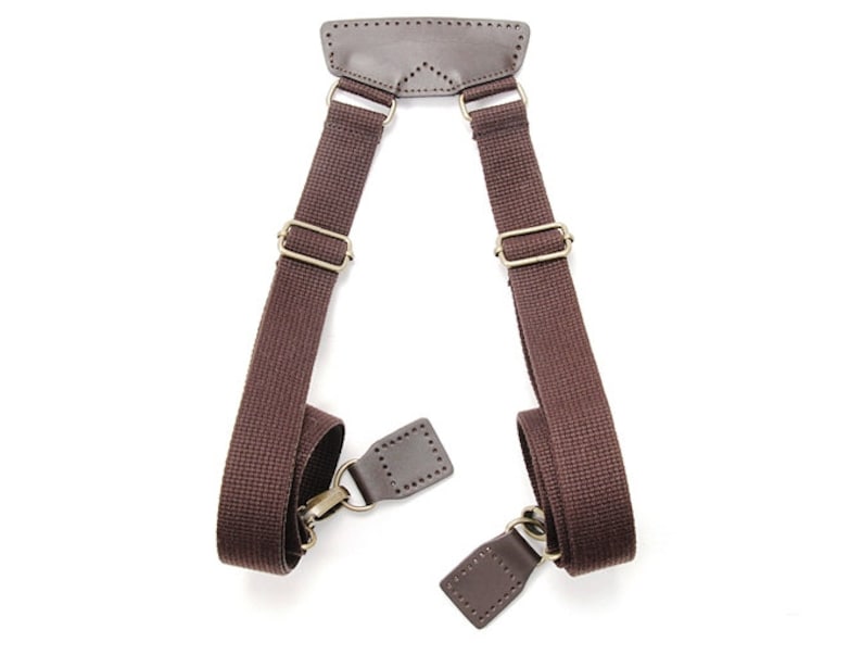 May include: Brown canvas shoulder straps with leather accents and brass hardware. The straps are designed to be used for a bag or other carrying device.