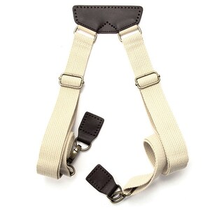 May include: A pair of beige canvas shoulder straps with brown leather accents and metal hardware. The straps are adjustable and can be used to carry a bag or other item.