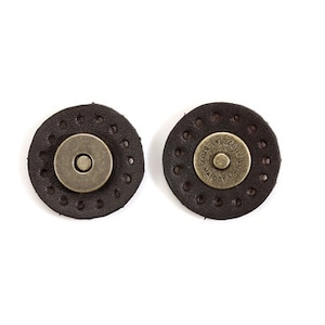 May include: Two brown leather magnetic closures with metal snaps. The snaps have the text "GOOD LUCK" and "MADE IN ITALY" on them.