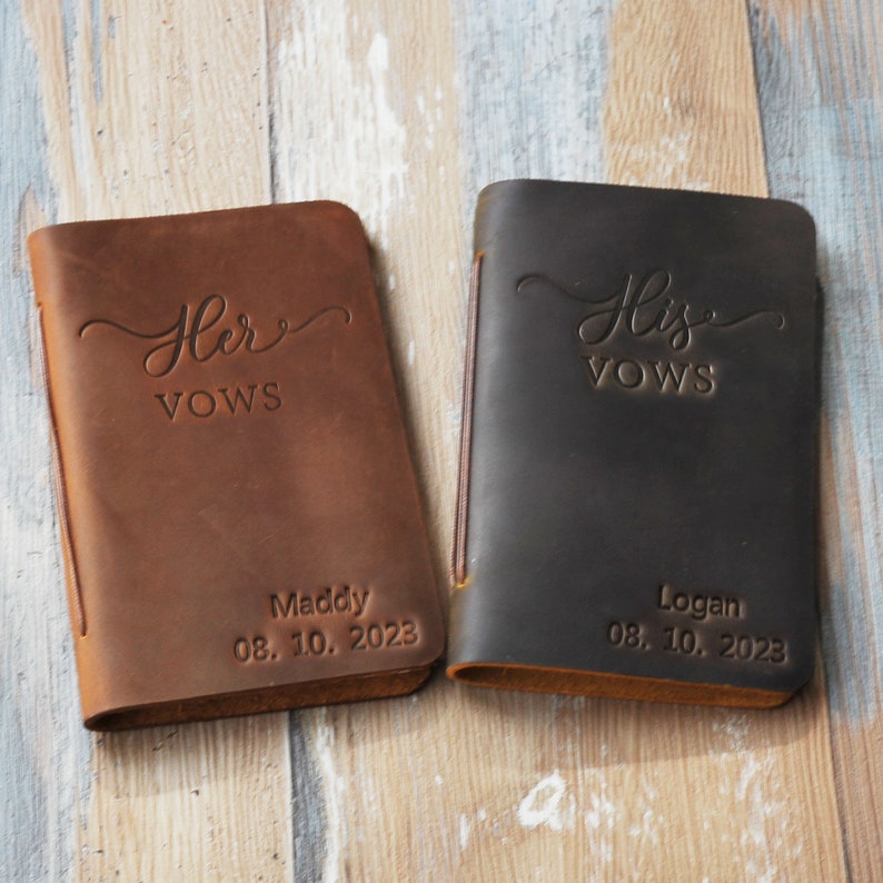 May include: Two brown leather vow books with the words "Her Vows" and "His Vows" embossed on the front. The books are personalized with the names "Maddy" and "Logan" and the date "08.10.2023".