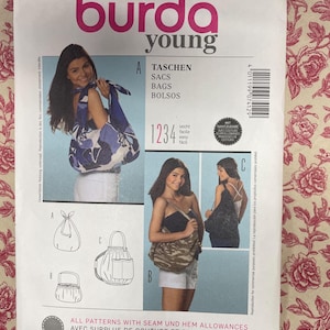 May include: A Burda Young sewing pattern for bags, featuring illustrations of different bag styles. The cover displays a woman with a bag, and the text includes "TASCHEN, SACS, BAGS, BOLSOS". The pattern number is 7412.