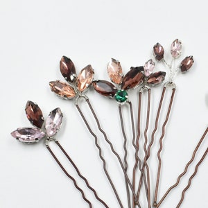 May include: Set of six hair pins with various floral designs featuring pink, brown, and green rhinestones. The pins are made of silver wire and have a brown, wavy metal base.