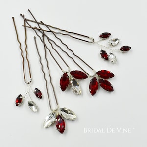 May include: Hair pins with red and clear crystal detailing. The pins feature a silver wire design with marquise-shaped crystals. The hair pins have a mix of clear and red crystals. The pins are set against a white background.