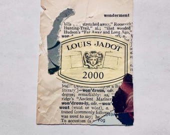May include: A rectangular collage piece featuring a vintage dictionary page with printed text, layered with a cream-colored Louis Jadot 2000 wine label. The label displays a central illustration of a face and the text Louis Jadot 2000.