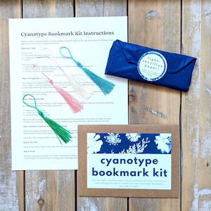 May include: Cyanotype bookmark kit with light-sensitive paper, instructions, and three green, pink, and cream tassels. The kit includes everything you need to create your own cyanotype bookmarks.