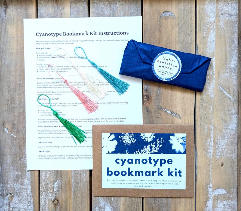 May include: Cyanotype bookmark kit with light-sensitive paper, instructions, and three green, pink, and cream tassels. The kit includes everything you need to create your own cyanotype bookmarks.