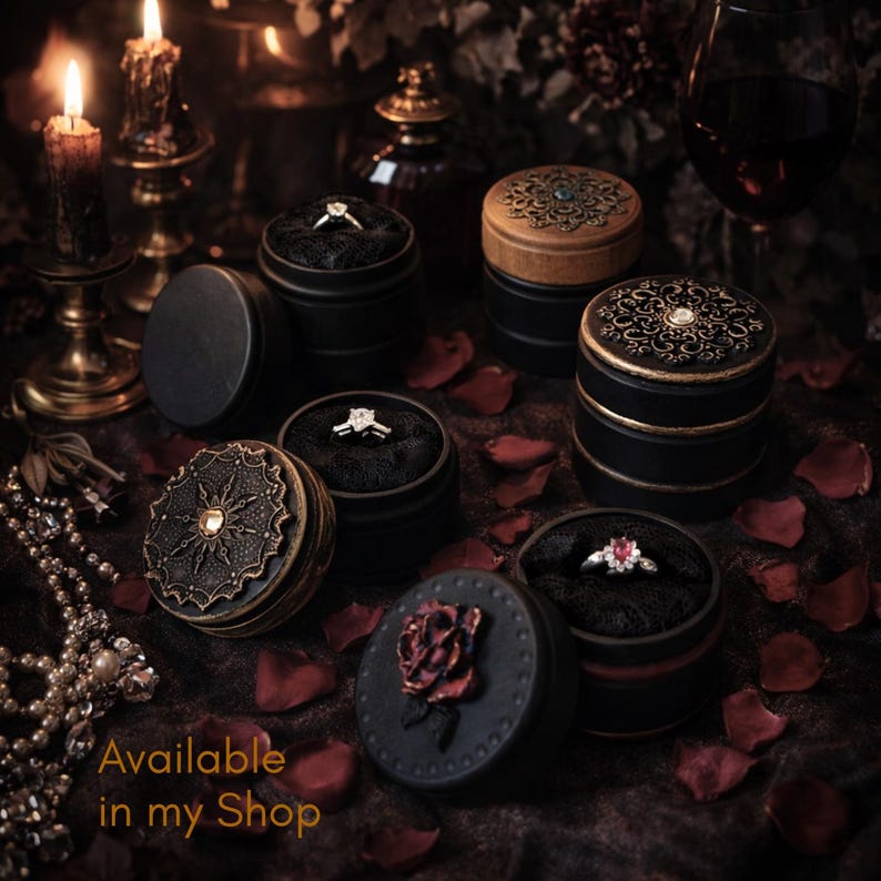 May include: Several black ring boxes with ornate lids, each containing a ring. Some boxes have gold or bronze accents, and one features a rose. The text "Available in my Shop" is visible.