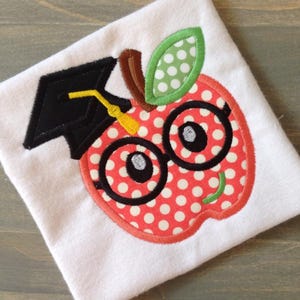 Disegno di ricamo a macchina con applicazione di mela con occhiali e cappello da laurea