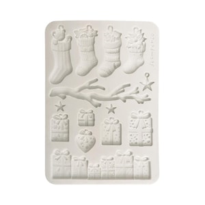 May include: A white rectangular silicone mold featuring various embossed holiday shapes including four Christmas stockings, a tree branch, two stars, and multiple gift boxes with bows. The word Stamperia is embossed on the right side.