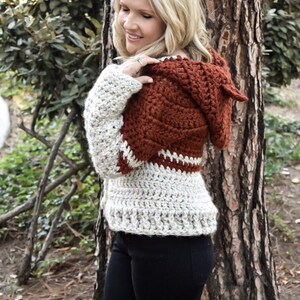 May include: A crocheted hooded sweater in a brown and white colour scheme. The sweater has a loose fit and a relaxed style.