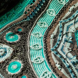 May include: A close-up of a crocheted blanket with a circular design in shades of brown, teal, and green.