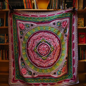 May include: A large, colorful crochet blanket with a mandala design in shades of pink, green, and yellow. The blanket is hanging on a bookshelf with books visible on the shelves. The text "SCHEEPJES CAL 2020" is visible at the bottom of the image.