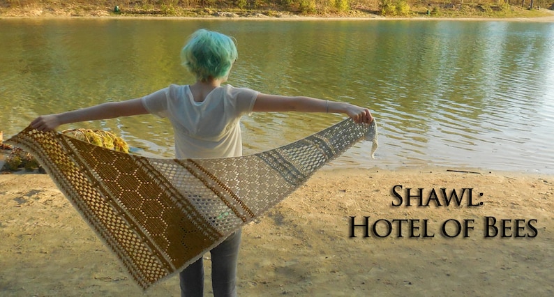 May include: A person wearing a white shirt and blue jeans holds a crocheted shawl with a honeycomb pattern in shades of brown, beige, and white. The shawl is spread out behind the person, and the text "SHAWL: HOTEL OF BEES" is visible in the lower right corner of the image.