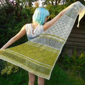 May include: A white and green crocheted shawl with a lacy pattern. The shawl is draped over a person's shoulders.