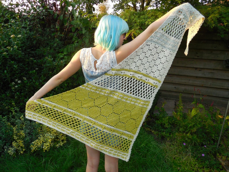 May include: A white and green crocheted shawl with a lacy pattern. The shawl is draped over a person's shoulders.