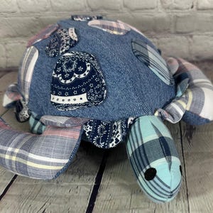 May include: A blue and pink patchwork fabric turtle toy. The turtle is made from denim, plaid, and paisley fabrics.