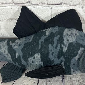 Op de afbeelding: Een grijze en zwarte pluche vis met een camouflagepatroon. De vis heeft een grote staartvin en twee rugvinnen. De vis heeft een knoopoog.