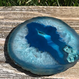 May include: A blue agate slice with white and light blue banding. The agate is polished and has a smooth surface.