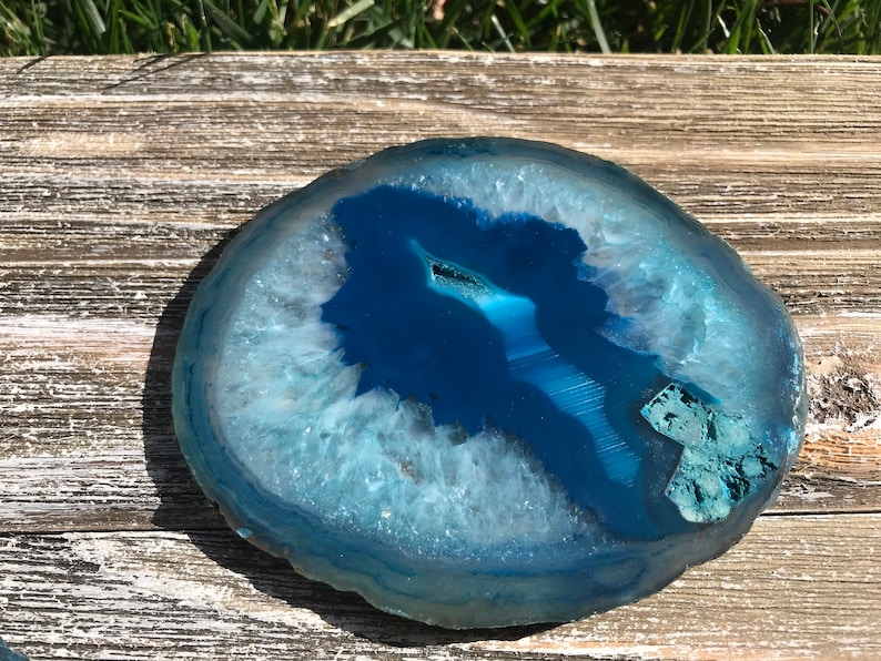 May include: A blue agate slice with white and light blue banding. The agate is polished and has a smooth surface.