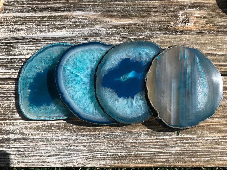 May include: Four agate coasters in shades of blue and white. The coasters are round and have a natural, polished finish.