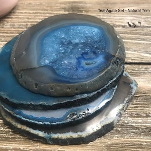 May include: Teal agate coasters with natural trim. The coasters are stacked on top of each other, showing the blue and gray agate pattern.