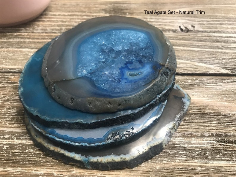 May include: Teal agate coasters with natural trim. The coasters are stacked on top of each other, showing the blue and gray agate pattern.