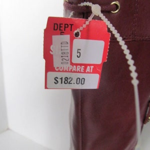 Puede incluir: Bota de cuero roja con ojales dorados y una etiqueta blanca que dice "DEPT 5 COMPARE AT $182.00"