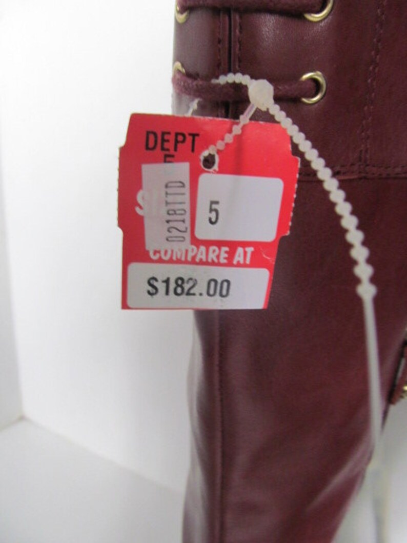 Puede incluir: Bota de cuero roja con ojales dorados y una etiqueta blanca que dice "DEPT 5 COMPARE AT $182.00"