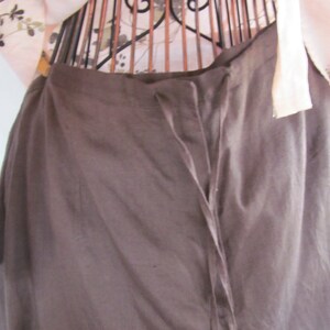May include: A brown skirt with a drawstring waist and a long, flowing silhouette.