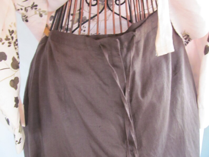 May include: A brown skirt with a drawstring waist and a long, flowing silhouette.