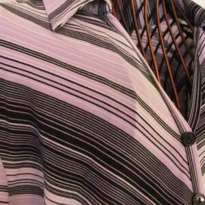 May include: A long-sleeved shirt with a striped pattern in shades of purple, black, and white. The shirt has a button-down collar and a V-neckline.