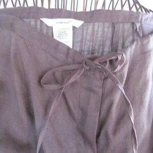 May include: Brown linen trousers with a drawstring waist and a white label that says "white+warren".