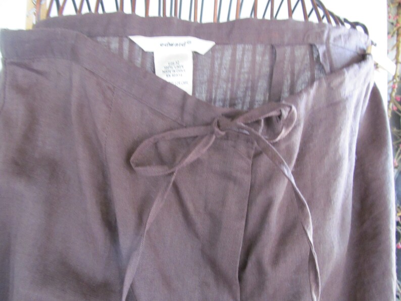 May include: Brown linen trousers with a drawstring waist and a white label that says "white+warren".