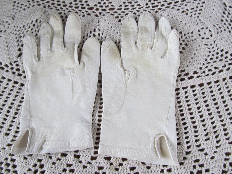 Puede incluir: Un par de guantes de cuero blanco con un dise&ntilde;o sencillo. Los guantes est&aacute;n hechos de cuero suave y flexible y tienen un acabado liso.