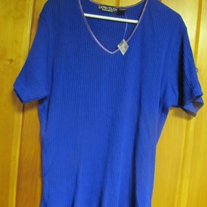 May include: A royal blue ribbed short-sleeved shirt with a purple v-neck trim. The shirt has the text "EXTRA TOUCH" on the tag.