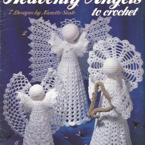 May include: A leaflet cover featuring three white crocheted angel figures with detailed wings. The text "Heavenly Angels to crochet" is displayed above the figures. The leaflet is titled "7 Designs by Nanette Seale."