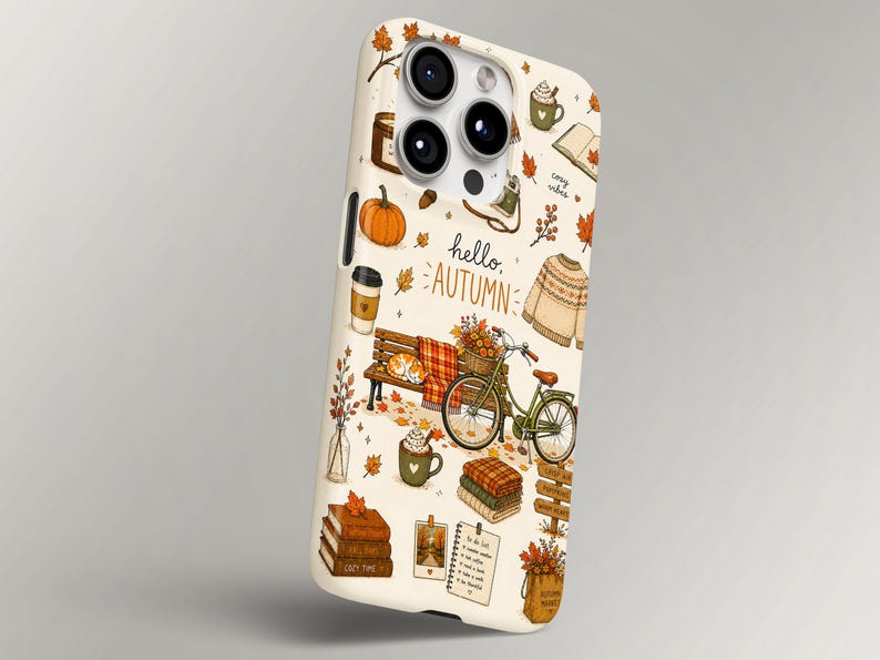 May include: A cream-colored smartphone case featuring a repeating pattern of autumn-themed illustrations including a pumpkin, a bicycle, a bench, a sweater, books, and mugs. The text "hello, AUTUMN" is printed in the center in a dark brown script font.