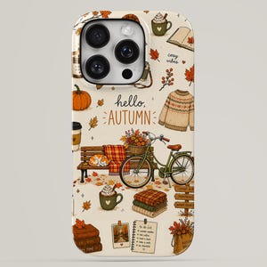 May include: A cream-colored phone case featuring an autumn-themed pattern with pumpkins, a bicycle, a sweater, mugs of hot cocoa, stacks of books, and fallen leaves. The text hello, AUTUMN is printed in the center with additional cozy vibes text.