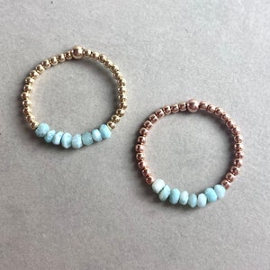 Puede incluir: Dos pulseras delicadas con una fila de cuentas de piedras preciosas azul claro y cuentas de oro y oro rosa.