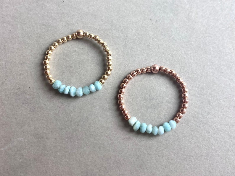 Puede incluir: Dos pulseras delicadas con una fila de cuentas de piedras preciosas azul claro y cuentas de oro y oro rosa.