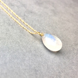 May include: A gold chain necklace with a teardrop-shaped moonstone pendant.