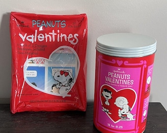 May include: A set of Peanuts Valentine's Day cards in a red plastic bag and a tin container. The bag contains 30 cards with 5 different designs. The tin container contains 18 cards with a different design. Both packages feature Peanuts characters like Charlie Brown, Snoopy, and Lucy.